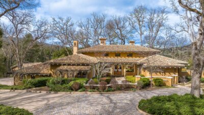 A front exterior photo of a home surrounded by trees and bushes on 38 Arroyo Sequoia at the Santa Lucia Preserve.