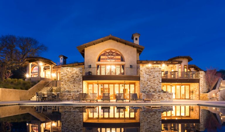 An exterior night photo of the two story house and pool on 16 Vasquez Trail at the Santa Lucia Preserve.